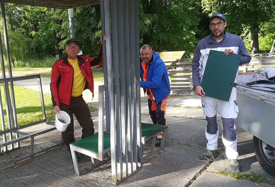 Kurt Kernstock und Norbert Frey montieren die Sitzflächen, die Andreas Frank (v.l.) neu gestrichen hat. Foto: Zur Verfügung